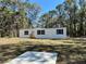 Charming manufactured home featuring white siding, dark shutters, and a serene wooded surrounding at 1921 Nw 120Th Ave, Ocala, FL 34482