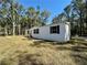 Side view of the manufactured home, boasting a well-maintained lawn and classic white siding at 1921 Nw 120Th Ave, Ocala, FL 34482