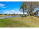 Expansive backyard with a tranquil pond view, mature trees, and lush green lawn on a sunny day at 1956 Nw 50Th Cir, Ocala, FL 34482