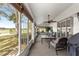 Enclosed lanai featuring a ceiling fan, comfortable seating, and views of the lush backyard and pond at 1956 Nw 50Th Cir, Ocala, FL 34482