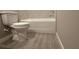 Bathroom featuring a white toilet, white shower/tub and light-grey wood-look tile floors at 2602 Sw 154Th Ln, Ocala, FL 34473