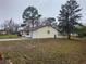 Single story home with tan siding, attached one car garage, and mature trees in the yard at 9021 Se 79Th Avenue Rd, Ocala, FL 34472