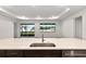 Modern kitchen island with stainless steel sink, dark cabinets and light countertops with views to the backyard at 10557 Sw 98Th Ln, Ocala, FL 34481