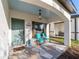 Inviting front porch features stylish stone flooring, relaxing chairs, and a decorative green door at 10597 Grand Oaks Blvd, Oxford, FL 34484