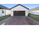Spacious two-car garage with brick paver driveway and exterior lighting at 10597 Grand Oaks Blvd, Oxford, FL 34484