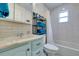 Well-lit bathroom featuring blue vanity, sink, toilet, and tiled shower with a curtain at 11720 Cherokee Cir, Dunnellon, FL 34431