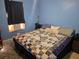 Bedroom with colorful quilt, window AC unit, blue walls and dark curtain at 11860 Nw 18Th Pl, Ocala, FL 34482