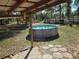 Above-ground pool in a backyard setting with mature trees, grass and stepping stones at 11860 Nw 18Th Pl, Ocala, FL 34482