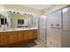 Bright bathroom featuring a dual sink vanity, a large mirror, and a glass enclosed shower at 12133 Se 91St Ter, Summerfield, FL 34491