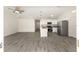 Open-concept living area with gray wood-look flooring flowing into a kitchen with stainless steel appliances at 127 Sw Alvarez Rd, Dunnellon, FL 34431