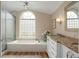 Bathroom featuring a soaking tub with a glass-block window and a granite-topped vanity at 2318 Nw 50Th Ave, Ocala, FL 34482