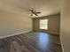 Large primary bedroom featuring hard surface floors, a ceiling fan, and a window overlooking a wooded backyard at 25 Olive Circle Loop, Ocala, FL 34472