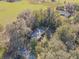 Aerial view of a home with a pond nearby, surrounded by a dense forest canopy at 324 S Highland St, Bushnell, FL 33513