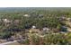 Aerial view of a home with a long driveway and a detached garage surrounded by lush trees at 4826 Sw Dahlia Ct, Dunnellon, FL 34431