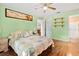 Bright bedroom featuring a ceiling fan, wooden floors, decorative shelves, and comfortable-looking quilted bedding at 53 Juniper Trail Cir, Ocala, FL 34480