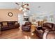 Spacious living room with leather furniture, wood floors, ceiling fan, and an open layout to the dining area and kitchen at 53 Juniper Trail Cir, Ocala, FL 34480