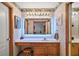 Well-lit bathroom with a wooden vanity, a large illuminated mirror, and wallpapered walls at 5926 Ne 62Nd Court Rd, Silver Springs, FL 34488