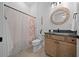 Clean bathroom with a vanity, a granite countertop, custom mirror, and a shower with a decorative seashell curtain at 8825 Sw 57Th Place Rd, Ocala, FL 34481