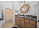Well-lit bathroom featuring a granite countertop, wooden cabinets, and decorative round mirror at 8825 Sw 57Th Place Rd, Ocala, FL 34481