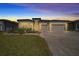 Charming home features a well-manicured lawn, colorful plants, and a brick paver driveway illuminated by evening lights at 8825 Sw 57Th Place Rd, Ocala, FL 34481