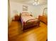 Well lit bedroom with hardwood floors, colorful quilt, and matching bedside lamps at 10076 Se 139Th Pl, Summerfield, FL 34491