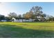 Spacious backyard featuring a lush lawn, mature trees, and various outbuildings, perfect for outdoor activities and relaxation at 10495 Sw 100Th Ave, Ocala, FL 34481