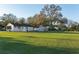 A spacious backyard with a well-maintained lawn, mature trees, and outbuildings, offering plenty of room for recreation and leisure at 10495 Sw 100Th Ave, Ocala, FL 34481