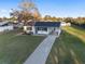 A well-maintained single-story home with a long driveway and green lawn at 10495 Sw 100Th Ave, Ocala, FL 34481