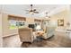 Bright living room featuring wood floors, comfortable armchairs, and views of the serene backyard at 11013 Se 169Th Pl, Summerfield, FL 34491