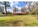 Expansive front lawn leads to a brick home with a striking red roof and a cozy front porch at 1300 Ne 53Rd St, Ocala, FL 34479