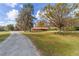 View of the expansive front yard with lush green grass, and a long driveway leading up to the charming home at 1300 Ne 53Rd St, Ocala, FL 34479