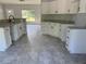 Modern kitchen with white cabinets, granite countertops, stainless steel appliances, and gray tile flooring at 14 Bay Terrace Pass, Ocklawaha, FL 32179