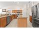 Well-lit kitchen features wood cabinets, modern stainless-steel appliances, and stylish tile flooring at 17 Pine Course Loop, Ocala, FL 34472