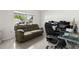 Bright living room features tile floors, a comfortable couch, an office chair, and natural light from a window at 17 Pine Course Loop, Ocala, FL 34472