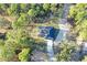An aerial view of a home surrounded by trees, featuring a driveway that leads to a house with a dark roof at 17710 Sw 48Th Pl, Dunnellon, FL 34432