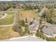 Aerial view of a tan home with a brown roof, mature trees, and a large grassy field nearby at 1835 Se 22Nd St, Ocala, FL 34471