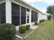 View of screened-in back patio with trimmed shrubbery, green grass, and access to backyard at 2459 Nw 55Th Avenue Rd, Ocala, FL 34482