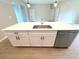 Stylish kitchen island with stainless steel sink, modern faucet, white cabinets, and stainless steel dishwasher at 4059 Sw 131St Place Rd, Ocala, FL 34473