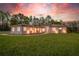 Charming single-story home with well-manicured lawn and beautiful landscape under a colorful sunset sky at 4869 Nw 101St Street Rd, Ocala, FL 34482