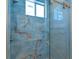 Elegant bathroom featuring blue marble-look tile and frameless glass shower doors at 4869 Nw 101St Street Rd, Ocala, FL 34482