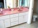 Bathroom featuring double pink sinks, white cabinetry providing ample storage, and a toilet, blending style with functionality at 5181 Sw 164Th Street Rd, Ocala, FL 34473