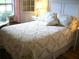 Charming bedroom featuring a floral-patterned quilt and matching pillows, complemented by a bright window and soft lighting at 5181 Sw 164Th Street Rd, Ocala, FL 34473