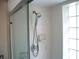Shower with a glass door, neutral tile, and clear glass block window, providing natural light and a modern touch at 5181 Sw 164Th Street Rd, Ocala, FL 34473