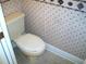 Toilet in a small bathroom with patterned walls and neutral floors, showcasing efficient use of space and a functional design at 5181 Sw 164Th Street Rd, Ocala, FL 34473
