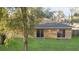 Backyard with lush green grass and a beige exterior, and two glass sliding doors at 5758 Nw 63Rd Pl, Ocala, FL 34482
