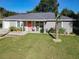 Charming single-story home with a well-manicured lawn, cute furniture set, and a striking orange front door at 634 Nw 56Th Ave, Ocala, FL 34482