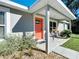 Inviting front porch featuring a cozy seating area and an eye-catching orange door at 634 Nw 56Th Ave, Ocala, FL 34482