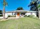 Charming single-story home with a well-manicured lawn, cute furniture set, and a striking orange front door at 634 Nw 56Th Ave, Ocala, FL 34482