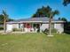 Charming single-story home with a well-manicured lawn, cute furniture set, and a striking orange front door at 634 Nw 56Th Ave, Ocala, FL 34482