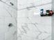 The bathroom shower features elegant marble-style tiles and a built-in shelf for toiletries and other bathing supplies at 634 Nw 56Th Ave, Ocala, FL 34482